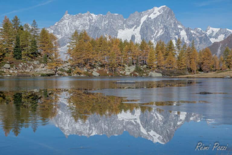 Lac de montagne reflétant les sommets enneigés alentours