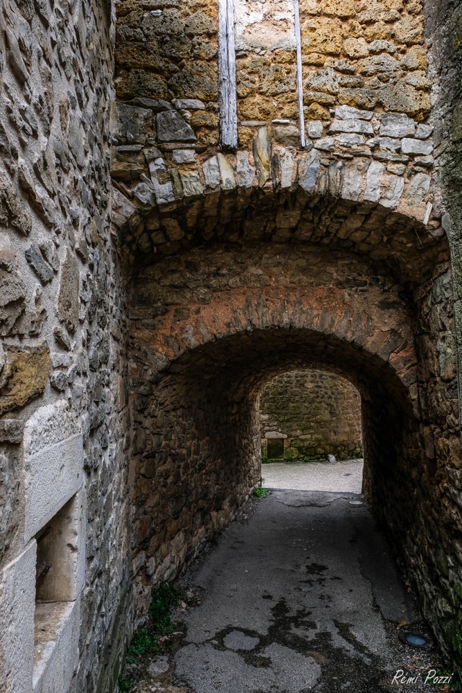 Passage escarpé sous une voute en pierre dans un village médiéval