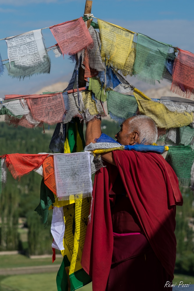 Moine bouddhiste sous les drapeaux de prières multicolores